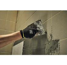 Obkladač nanáší lepidlo na stěnu pomocí špachtle