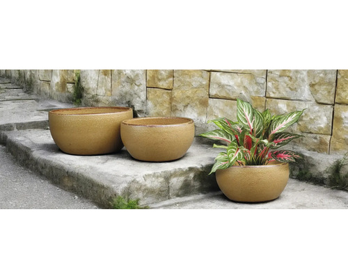 Tři kulaté květináče na kamenném schodišti, jeden z nich s rostlinou