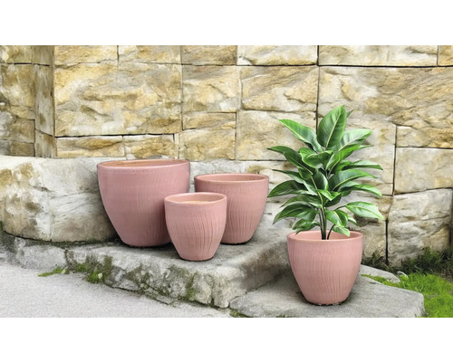 Květináče různých velikostí před kamennou zdí