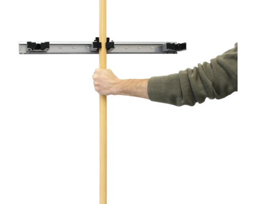 Muž upevňuje rukojeť do nástěnného držáku na nářadí