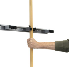 Ruka vkládá dřevěnou násadu do držáku na nářadí.