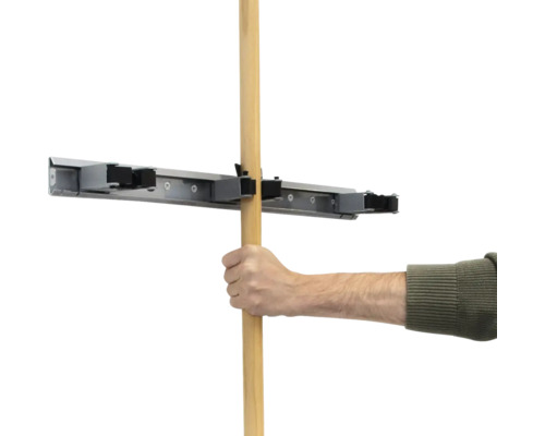 Ruka vkládá dřevěnou násadu do držáku na nářadí.