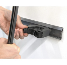 Osoba připevňuje nástroj k liště držáku nástrojů na zdi.