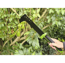 Osoba drží zahradní mačetu před zeleným živým plotem.