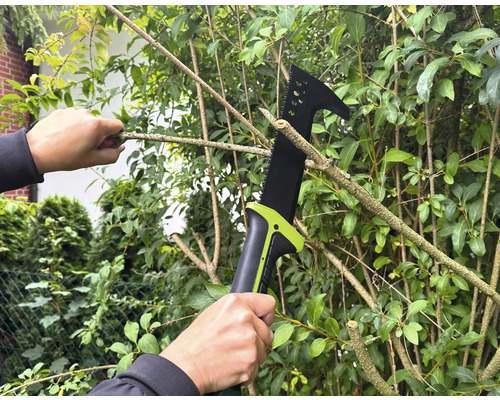 Osoba řeže větvě na stromě pomocí prořezávací pily