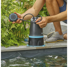 Muž obsluhuje jezírkové čerpadlo na okraji jezírka.