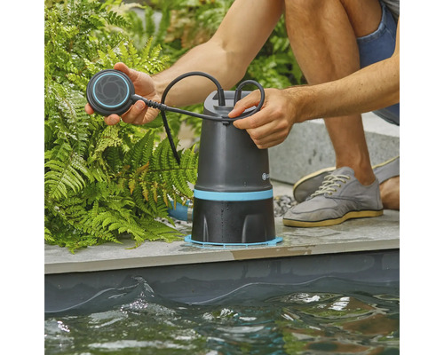 Muž obsluhuje jezírkové čerpadlo na okraji jezírka.