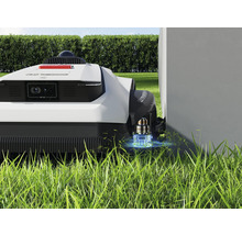 Robotická sekačka na trávníku blízko zdi