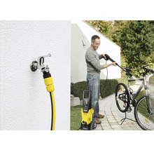 Muž čistí jízdní kolo pomocí vysokotlakého čističe Kärcher. Vidět je také vodovodní kohoutek s hadicovou přípojkou.