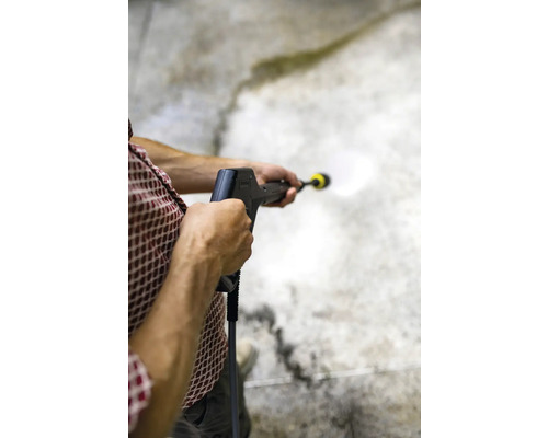 Osoba používá vysokotlaký čistič k čištění povrchu.