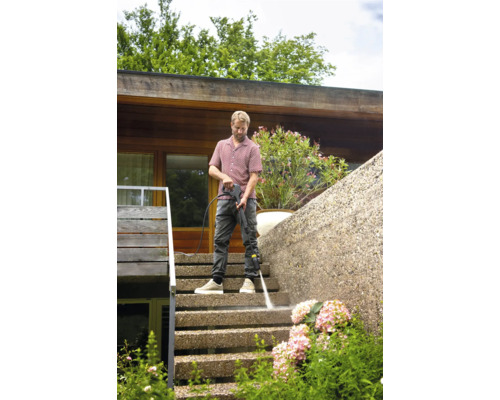 Muž čistí venkovní schody vysokotlakým čističem.