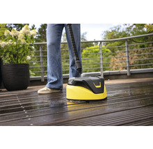 Osoba čistí dřevěnou terasu čističem povrchů.