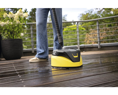 Osoba čistí dřevěnou terasu čističem povrchů.