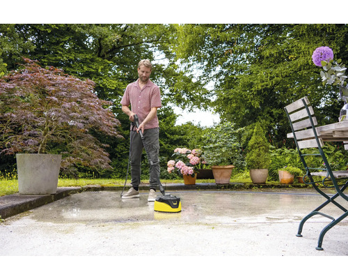 Muž čistí terasu čističem teras na zahradě.