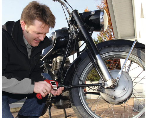 Muž opravuje motorku šroubovákem