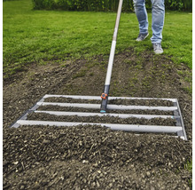 Úprava půdy pomocí urovnávací lišty na zahradě.