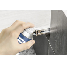 Ruka stříká kluzný sprej na výsuv zásuvky.