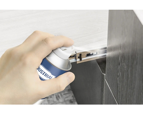 Ruka stříká kluzný sprej na výsuv zásuvky.