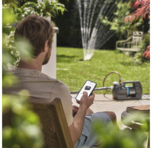 Muž ovládá zahradní čerpadlo pomocí aplikace pro chytré telefony na zahradě