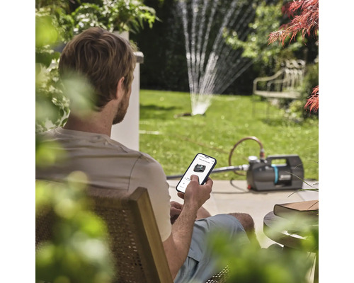 Muž ovládá zahradní čerpadlo pomocí aplikace pro chytré telefony na zahradě