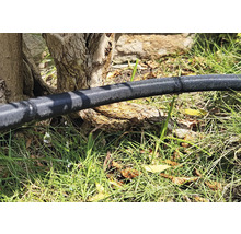 Zavlažovací hadice na zahradě s unikající vodou