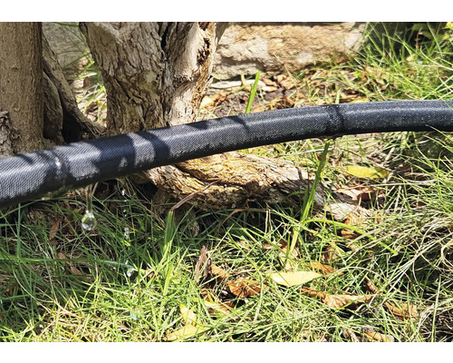 Zavlažovací hadice na zahradě s unikající vodou