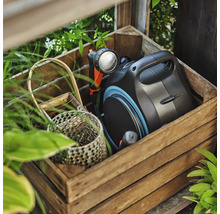 Box na zahradní hadici s rozstřikovací pistolí v dřevěné bedně