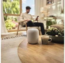 Chytrý reproduktor na kulatém dřevěném stole v obývacím pokoji