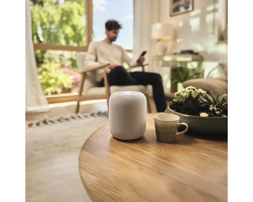 Chytrý reproduktor na kulatém dřevěném stole v obývacím pokoji