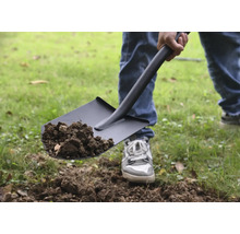 Osoba lopatou nabírá hlínu.