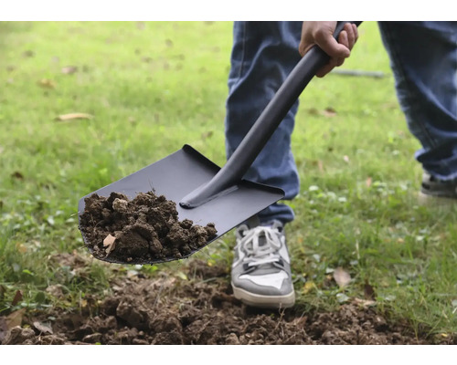 Osoba lopatou nabírá hlínu.