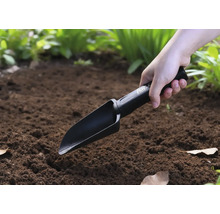 Osoba používá ruční lopatku na zahradě.