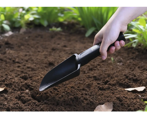 Osoba používá ruční lopatku na zahradě.