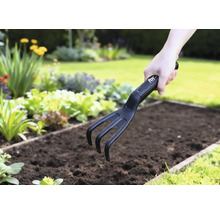 Zahradní kultivátor používaný v zeleninovém záhonu.