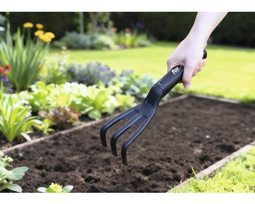 Zahradní kultivátor používaný v zeleninovém záhonu.