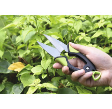 Ruka se zahradnickými nůžkami před zelenými rostlinami