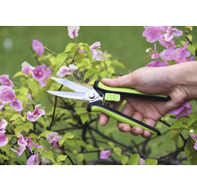 Zahradní nůžky v ruce před kvetoucí rostlinou