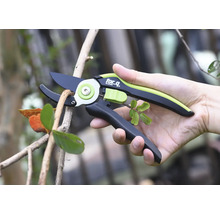 Osoba drží zahradní nůžky při stříhání větve.