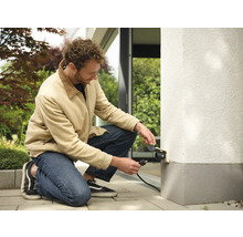 Muž připojuje venkovní zásuvku k domovní zdi