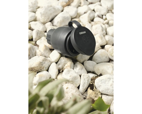 Logo Osram. Zahradní zásuvka s otevřeným víkem na štěrku.