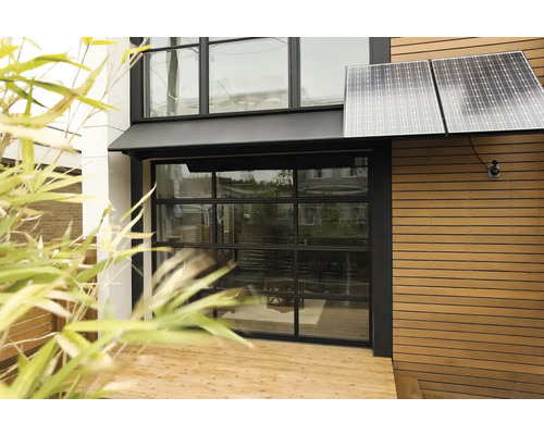 Vnější pohled na dům se solárními panely a skleněnými garážovými vraty