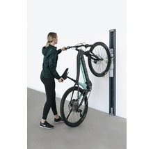 Žena zavěšuje elektrické horské kolo na nástěnný držák.