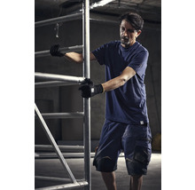 Muž v pracovním oděvu obsluhuje lešení.