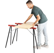 Muž pokládá dřevěnou desku na dvě kozy