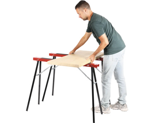 Muž pokládá dřevěnou desku na dvě kozy