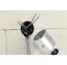 Stěna s vyvrtaným otvorem, elektrickými kabely a korunkovým vrtákem.