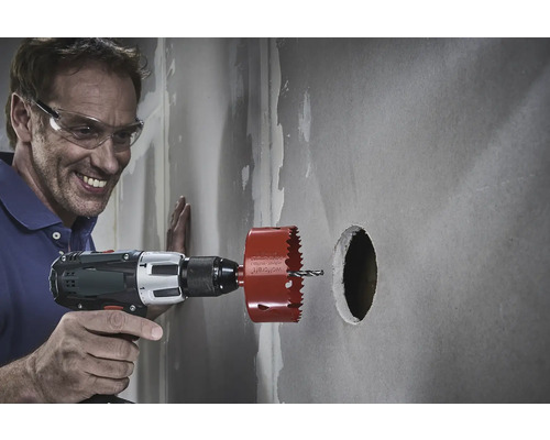 Muž vrtá do zdi otvor pomocí děrovací pily.