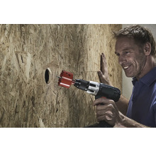 Muž vrtá děrovkou otvor do dřevěné desky.