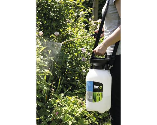 Osoba používá zahradní postřikovač for_q k postřiku rostlin.