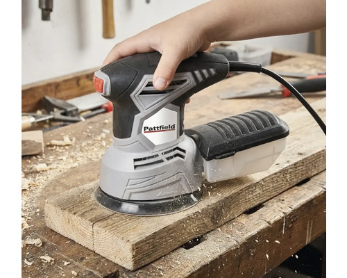 Ruka ovládá excentrickou brusku Pattfield na dřevěné desce.